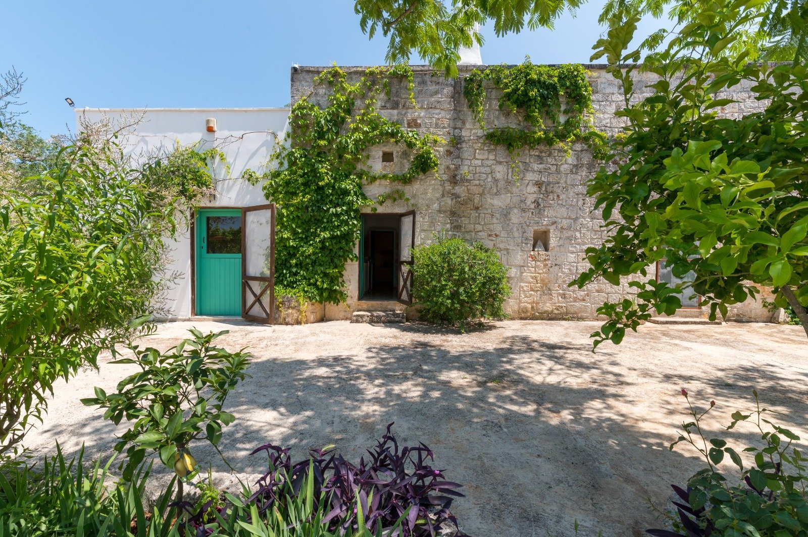 Stone courtyard with a green door at Masseria Bel Cortile