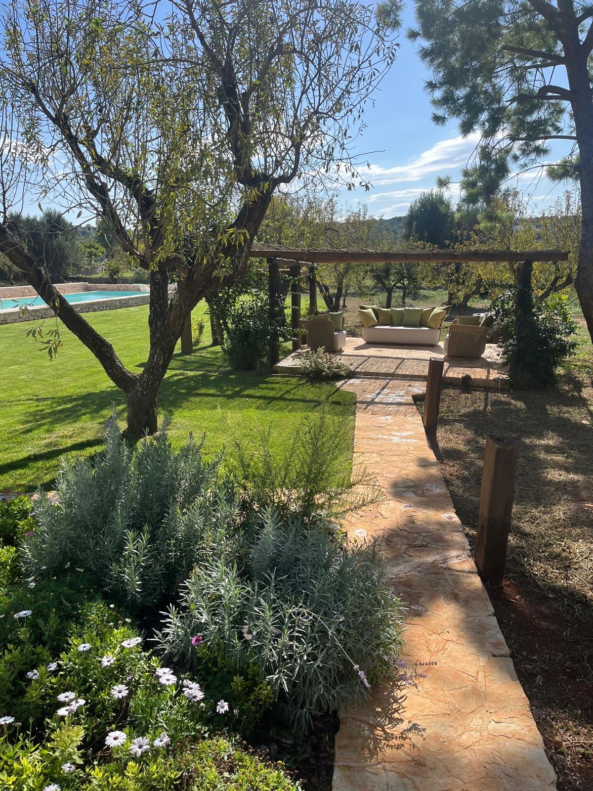 Stone path between lavender and flowers in the garden of the masseria