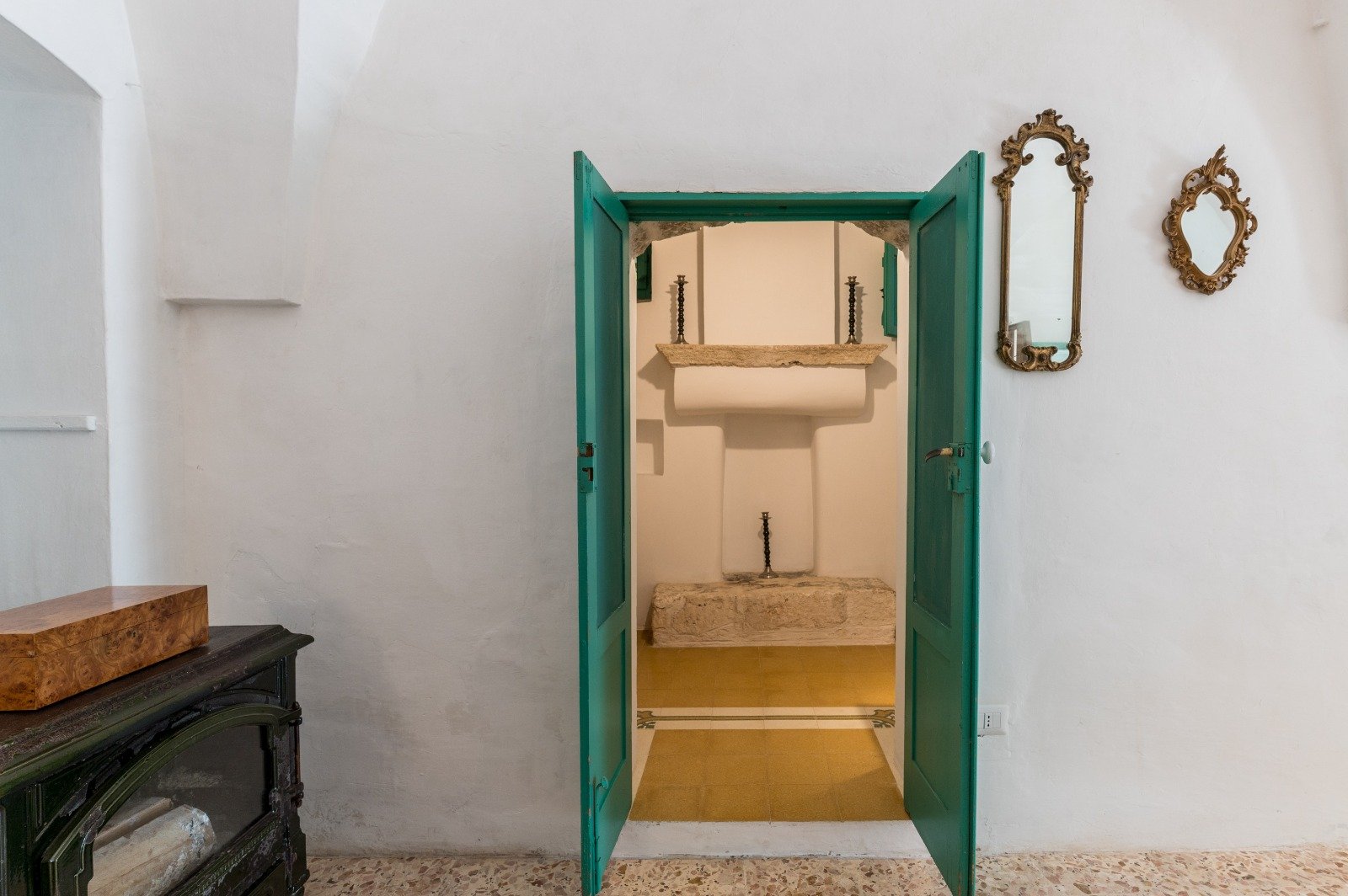 Bright interior with a green door and a mirror at the masseria