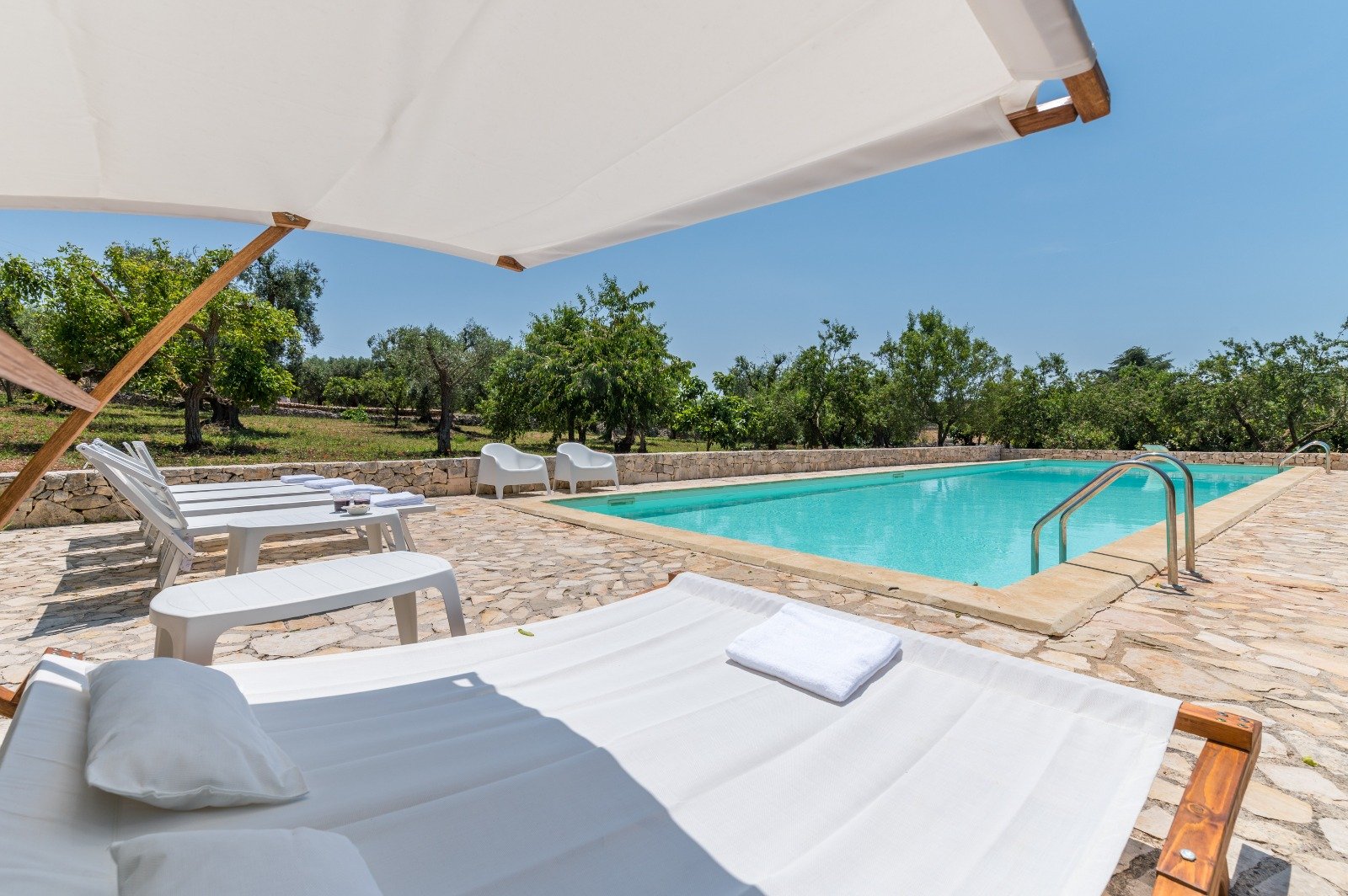 Pool with sun loungers and a parasol at Masseria Bel Cortile