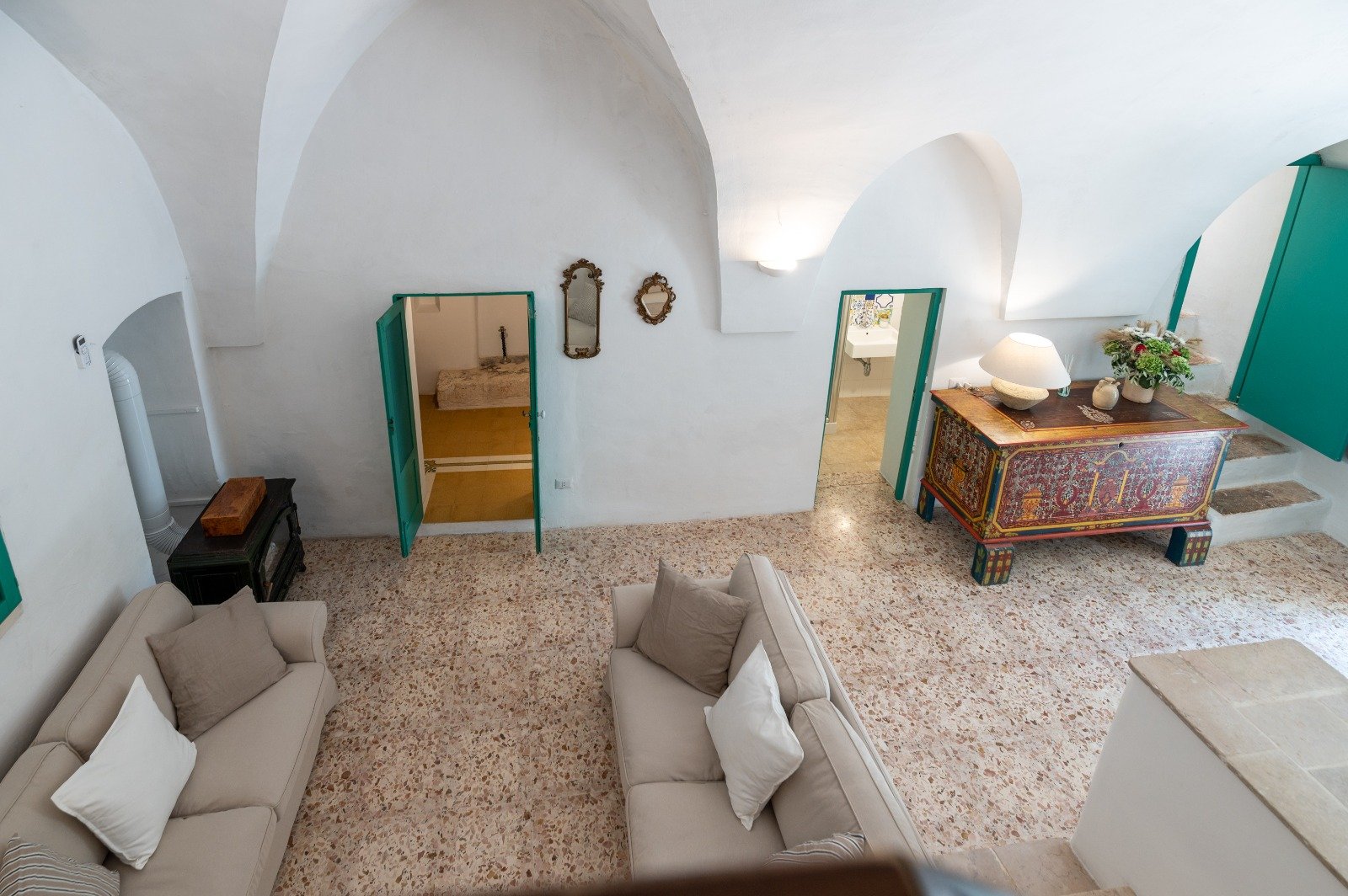Living room with stone vaults and green doors at the masseria in Ostuni